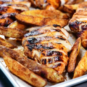 Buffalo chicken marinade grilled chicken on a sheet pan with potato wedges.